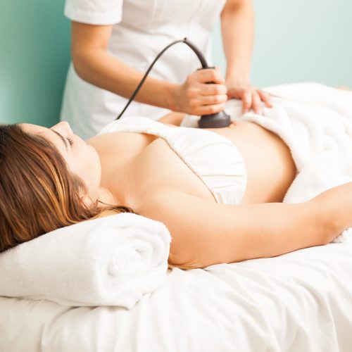 Female therapist giving a reductive and reaffirming treatment to a client and focusing on her belly